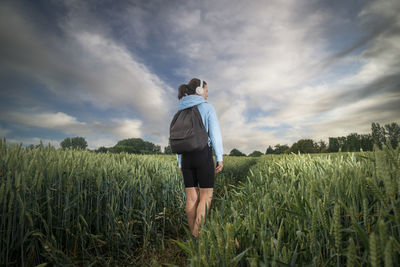 Woman with a backpack hiking through the countryside and fields. rear view,