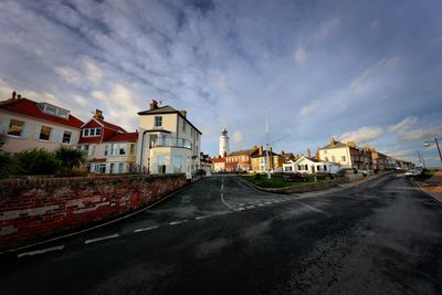 Road by houses against sky in city