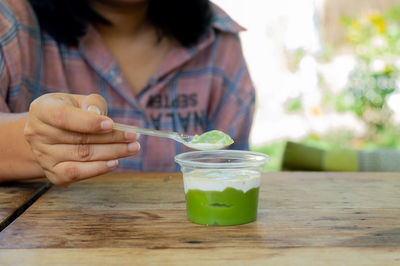 Midsection of woman holding drink on table