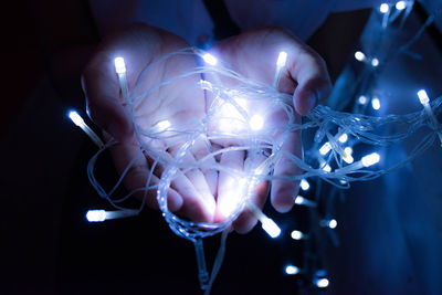 Close-up cropped hands holding illuminated lighting equipment