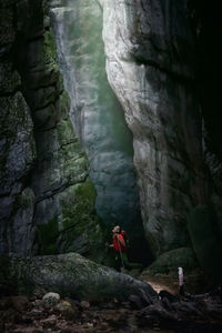 A man while inspecting a gorge, illuminated from above and surrounded by millenary rocks.