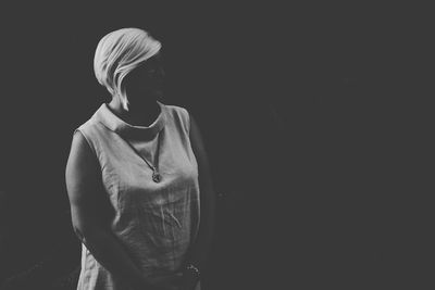 Full length of woman standing against black background