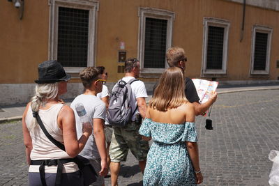 Rear view of people standing on street against buildings