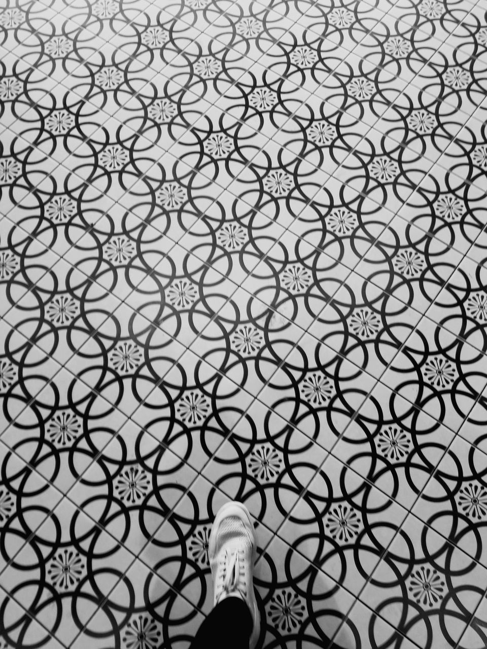 human leg, pattern, low section, shoe, human body part, real people, one person, personal perspective, body part, unrecognizable person, standing, flooring, design, lifestyles, human foot, day, leisure activity, tile, shape, tiled floor, human limb, floral pattern