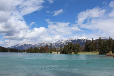 Scenic view of lake by snowcapped mountains against sky