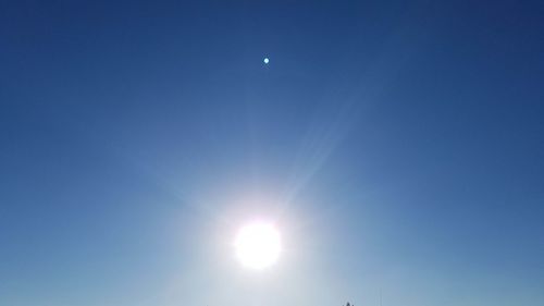 Low angle view of sun shining in blue sky