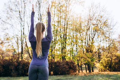 Rear view of woman with autumn leaves in park