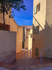 Alley amidst buildings against blue sky