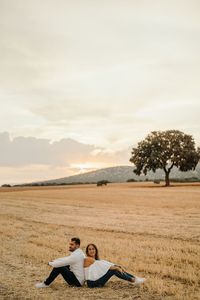 Young couple on field against sky