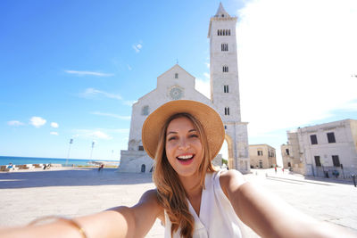 Beautiful tourist woman takes selfie with trani cathedral in apulia, italy