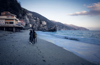 Rear view of people at beach against sky