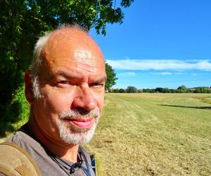 Portrait of smiling man on field against blue sky