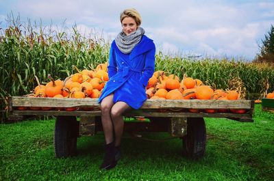 Portrait of woman sitting by pumpkin on wooden cart at laity pumpkin patch