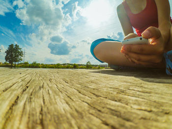 Low section of person on wood against sky