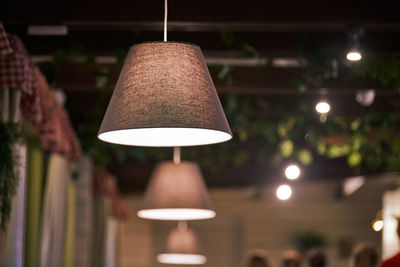 Pendant lamps over tables in city cafe, evening lighting restaurant. beige fabric lampshades