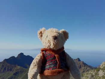 Close-up of stuffed toy on rock against blue sky