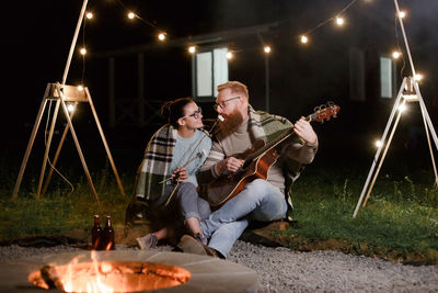 Friends sitting on illuminated stage at night