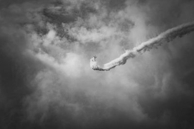Low angle view of airplane flying against cloudy sky