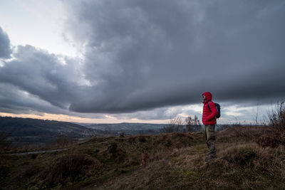 Woman standing on landscape against cloudy sky