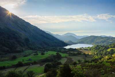 Scenic view of green landscape and mountains against sky