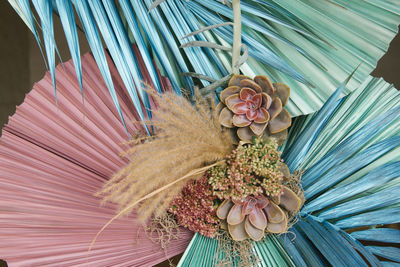 Creative composition of fresh succulents with gentle flowers and dry reeds arranged with colorful palm leaves of exotic plant in daytime