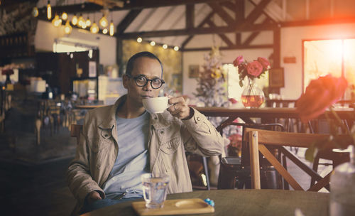 Portrait of man holding coffee cup sitting at restaurant