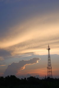 Low angle view of silhouette communications tower against sky during sunset
