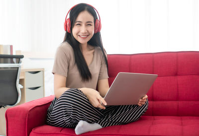 Young woman using phone while sitting on sofa