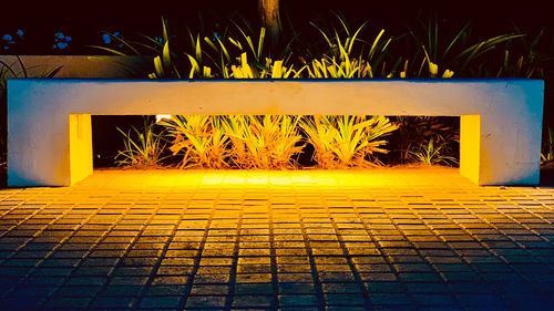 Illuminated footpath by street at night