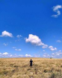 Man walking on field against blue sky