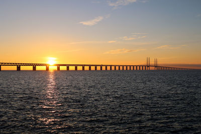 Sunset with the sun over the oresund bridge at the viewpoint near limhamn, sweden. clear sky, ship