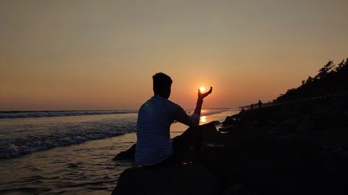 Silhouette man on beach against sky during sunset