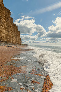 Rock formation on beach against sky