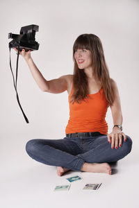 Beautiful woman taking selfie through camera against white background