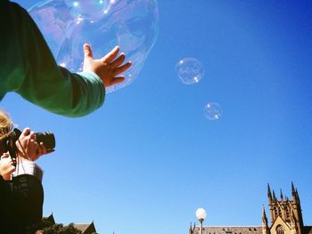 Low angle view of woman jumping in blue sky