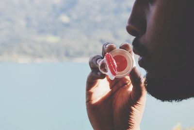 Side view of young man blowing bubble