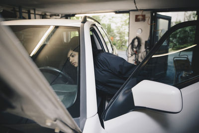 Female mechanic examining car at auto repair shop