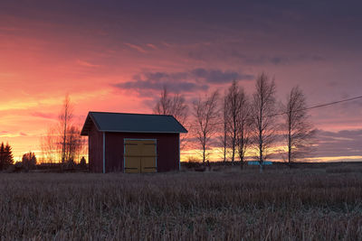 Silhouette house on field against sky during sunset