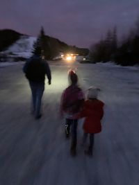 Rear view of people walking on snow during winter