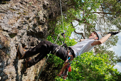 Full length of boy climbing on rock in forest