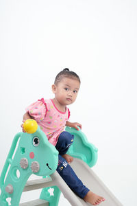 Portrait of cute baby boy with toy against white background