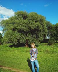 Woman standing on field against trees