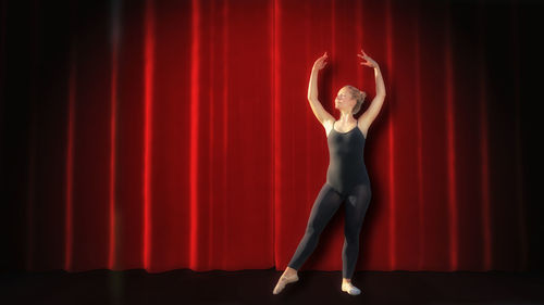 Full length of woman standing against red curtain