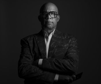 Portrait of bald man wearing suit standing against black background