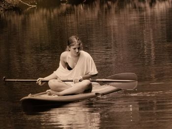 Young woman looking away while sitting on paddleboard