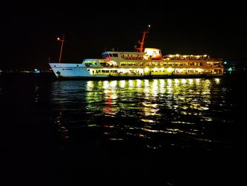 Illuminated ship in sea against sky at night