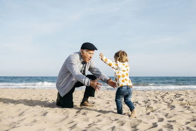 Grandfather playing with his granddaughter on the beach