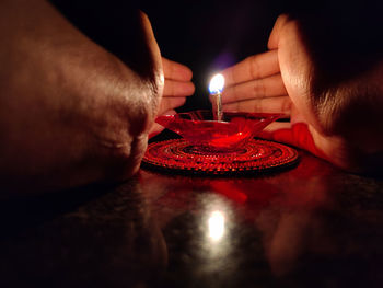 Close-up of hand holding lit candles