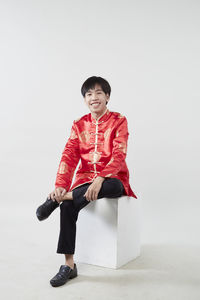 Full length of woman sitting against white background