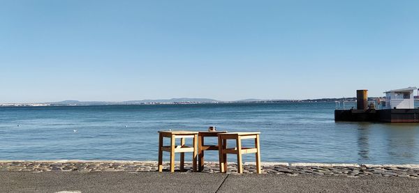 Chair on beach against clear blue sky